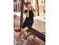 Une femme porte un t-shirt noir et un short tout en tenant un appareil photo Polaroid.