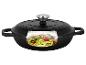 Cocotte en fonte noire avec couvercle, coupe transversale montrant des pâtes de courgettes aux tomates et pignons.