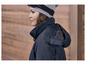 Une femme portant une veste bleue à capuche et un bonnet gris avec le logo 'CRIVIT'.