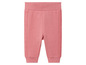 Pantalon de jogging rose avec des bordures côtelées sur les côtés.