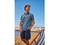 Homme en polo bleu et short cargo bleu sur la plage avec une chaise longue.