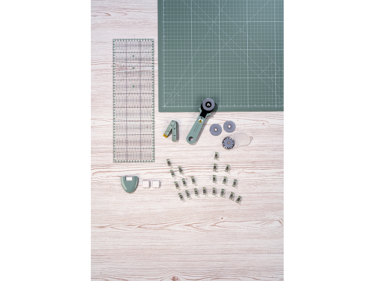 Kit de couture : tapis de coupe, règle, cutter rotatif, mètre ruban et pinces.