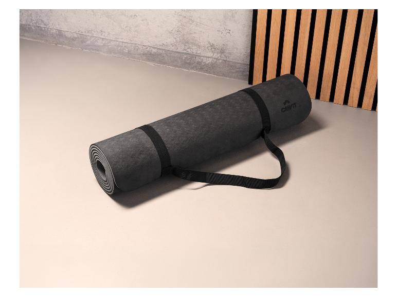Un tapis de yoga noir roulé de Crivit avec une sangle.