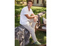 Un homme portant une chemise rayée, un pantalon beige et des baskets vertes dans le jardin.