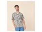 Homme en t-shirt rayé beige et bleu marine, pantalon en jean bleu, main dans la poche.