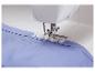 Une machine à coudre coud une boutonnière sur une chemise bleue.