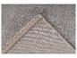 Tapis gris avec un coin replié montrant le dessous et le bord.