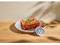 Lasagnes à la bolognaise avec basilic et tomates, avec une grille de hachoir sur une table en bois.