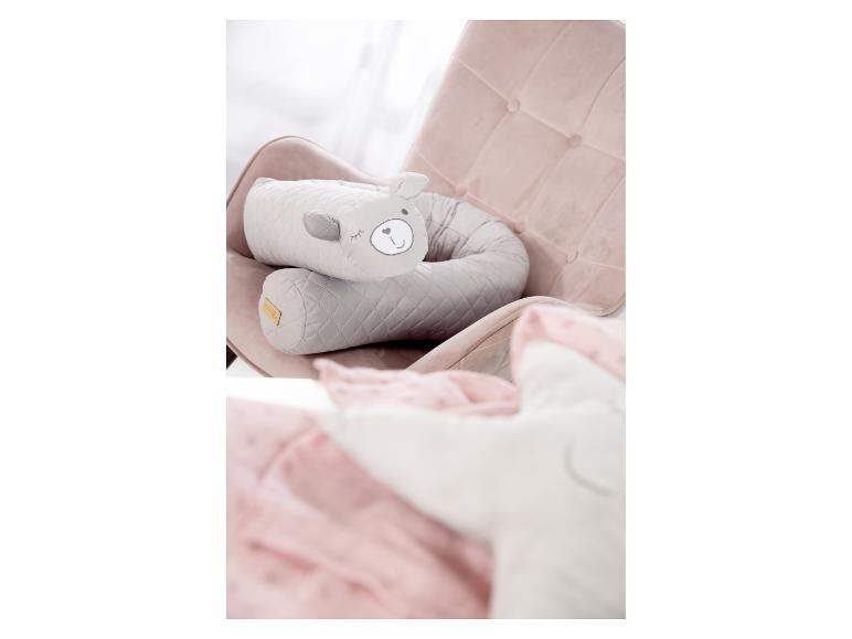 Coussin d'allaitement gris en forme d'ours sur un fauteuil rose avec une couverture rose.