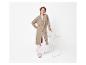Femme rousse en long cardigan beige, pantalon blanc et baskets.