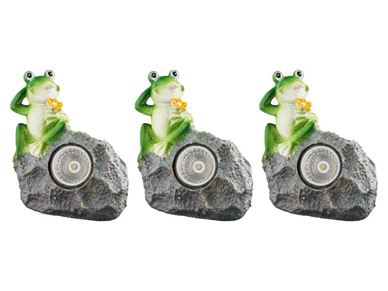 Trois lampes solaires en forme de grenouille sur rocher.