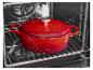 Cocotte en fonte rouge avec couvercle dans un four.