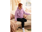 Femme en sweat à capuche violet et legging noir assise sur un canapé.