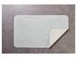 Un tapis de bain gris clair sur un sol en carrelage gris.