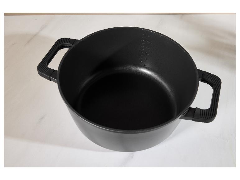 Marmite noire avec poignées et graduations sur une surface blanche.