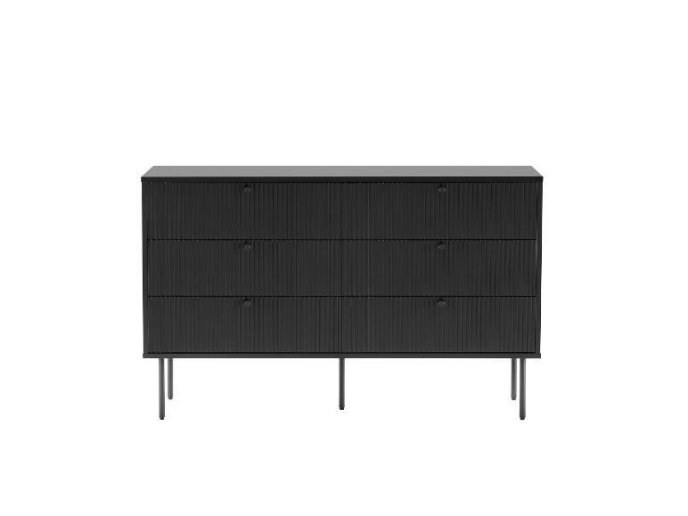 Commode noire à trois tiroirs avec façades cannelées sur pieds métalliques fins.