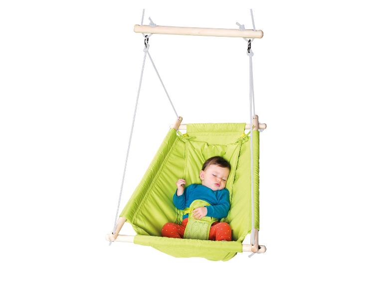 Un bébé dort dans une balançoire suspendue verte avec des sangles de sécurité.