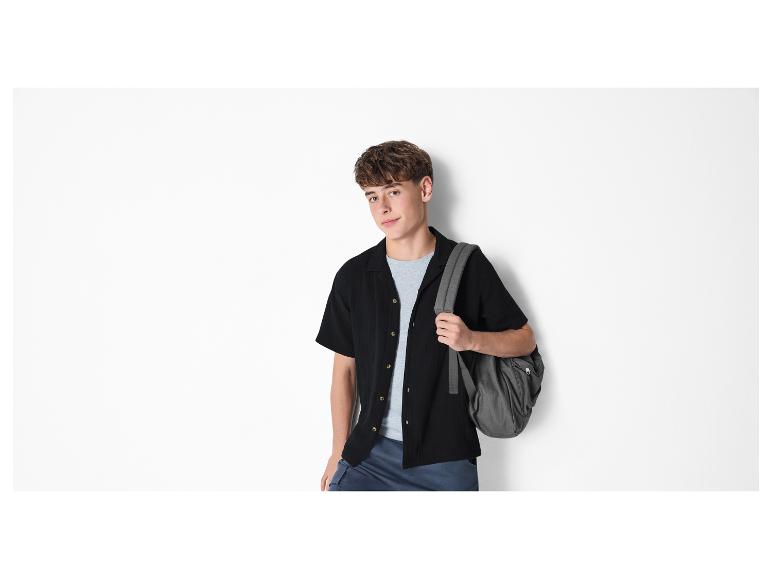 Jeune homme en chemise noire, t-shirt gris et sac à dos.