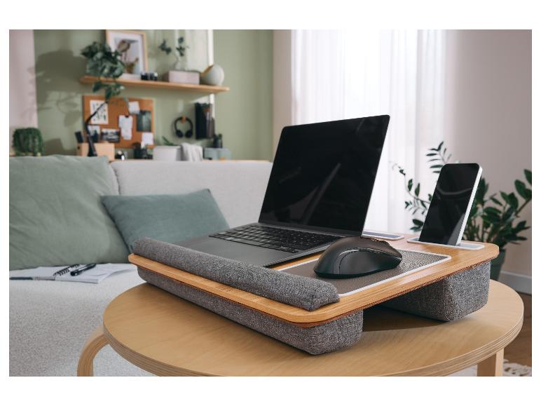 Ordinateur portable et smartphone sur un plateau de genoux en bois sur une table basse dans un salon.