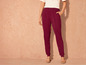 Une femme portant un pantalon bordeaux et un t-shirt blanc.