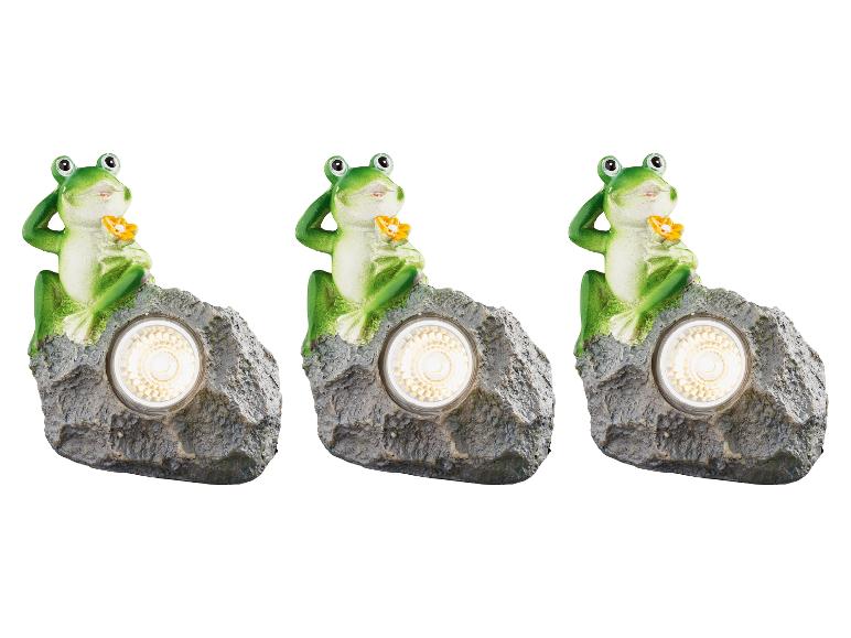 Trois lampes solaires en forme de grenouille sur roche.