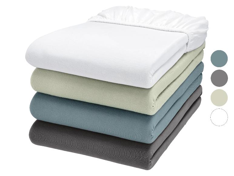 Pile de draps-housses blancs, vert clair, bleus et gris avec des échantillons de couleur.