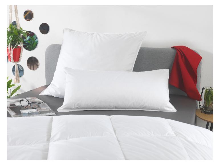 Lit avec oreillers blancs, couette et couverture rouge, avec plantes et miroirs décoratifs.