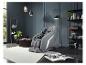 Fauteuil de massage gris dans un salon moderne avec étagères et plantes.