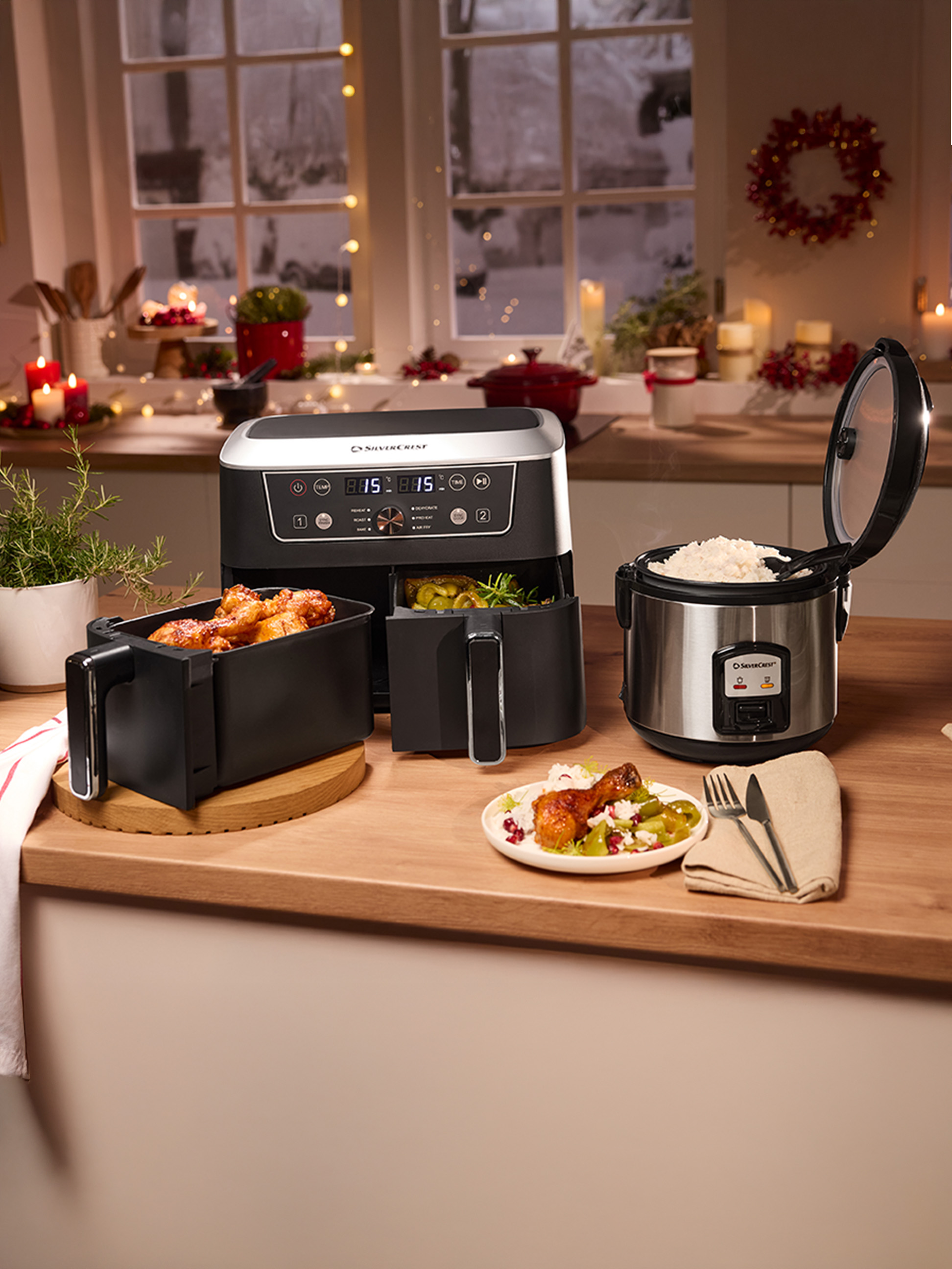 Friteuse à air Silvercrest et cuiseur à riz sur un comptoir de cuisine, avec des plats cuisinés et des décorations festives.
