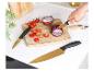 Deux couteaux dorés Russell Hobbs sont utilisés pour couper des oignons rouges et des tomates cerises sur une planche à découper en bois.