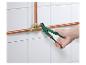 Un plombier utilise une pince à tuyaux verte pour connecter des tuyaux en cuivre.