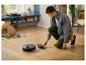Homme fixant un accessoire de nettoyage à un robot aspirateur sur un parquet.