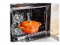 Une cocotte en fonte orange dans un four.