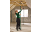Femme ajuste étai de construction télescopique, fixant plafond dans les combles.