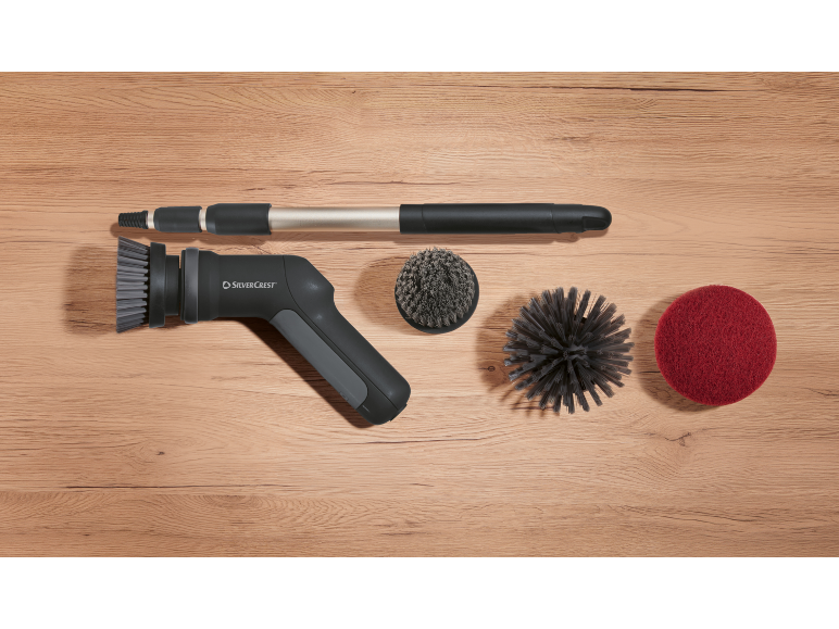 Kit de nettoyage avec brosse électrique, rallonge et divers accessoires sur fond en bois.