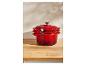 Ensemble de casseroles en fonte rouge empilées sur un comptoir en bois.