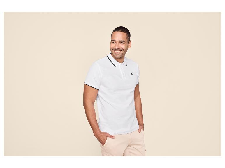 Homme en polo blanc à liseré noir et short cargo beige clair.