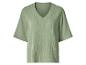 Chemisier vert clair à col en V et manches courtes, en tissu froissé.