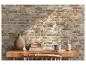 Bureau en bois avec livres, tasse et vases décoratifs devant un mur de briques rustique.