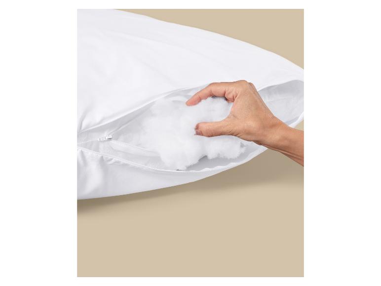 Main saisissant le rembourrage en coton d'un oreiller blanc zippé.