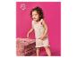 Bébé aux cheveux bouclés, portant un pyjama rose clair, jouant avec un jouet.
