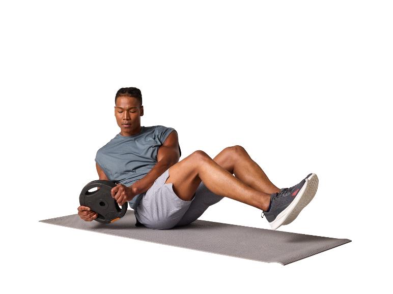 Homme faisant de l'exercice avec un disque de poids sur un tapis de yoga.