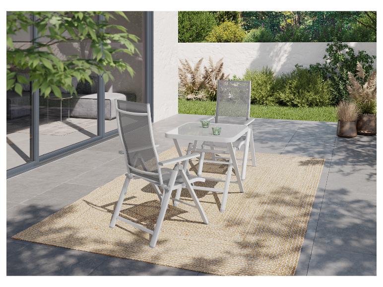 Ensemble repas extérieur avec deux chaises pliantes et une table sur une terrasse avec tapis.