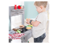 Enfant jouant avec un jouet barbecue en bois.