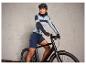 Une femme sur un vélo noir avec un short de vélo bleu et des vêtements de sport bleu et gris.