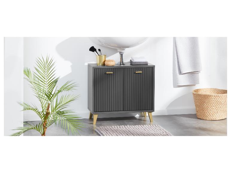 Une armoire de salle de bain gris foncé avec des pieds et des poignées dorés se trouve sur un tapis.