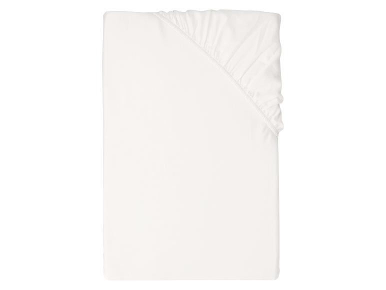 Drap-housse blanc plié avec un coin élastique.
