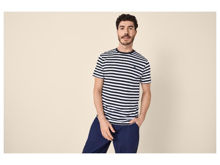 Homme en t-shirt rayé noir et blanc et pantalon bleu