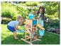 Deux enfants jouent avec un moulin à eau en bois et des seaux dans le jardin.
