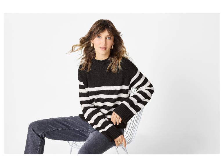 Femme en pull rayé noir et blanc et jean foncé assise sur une chaise blanche.